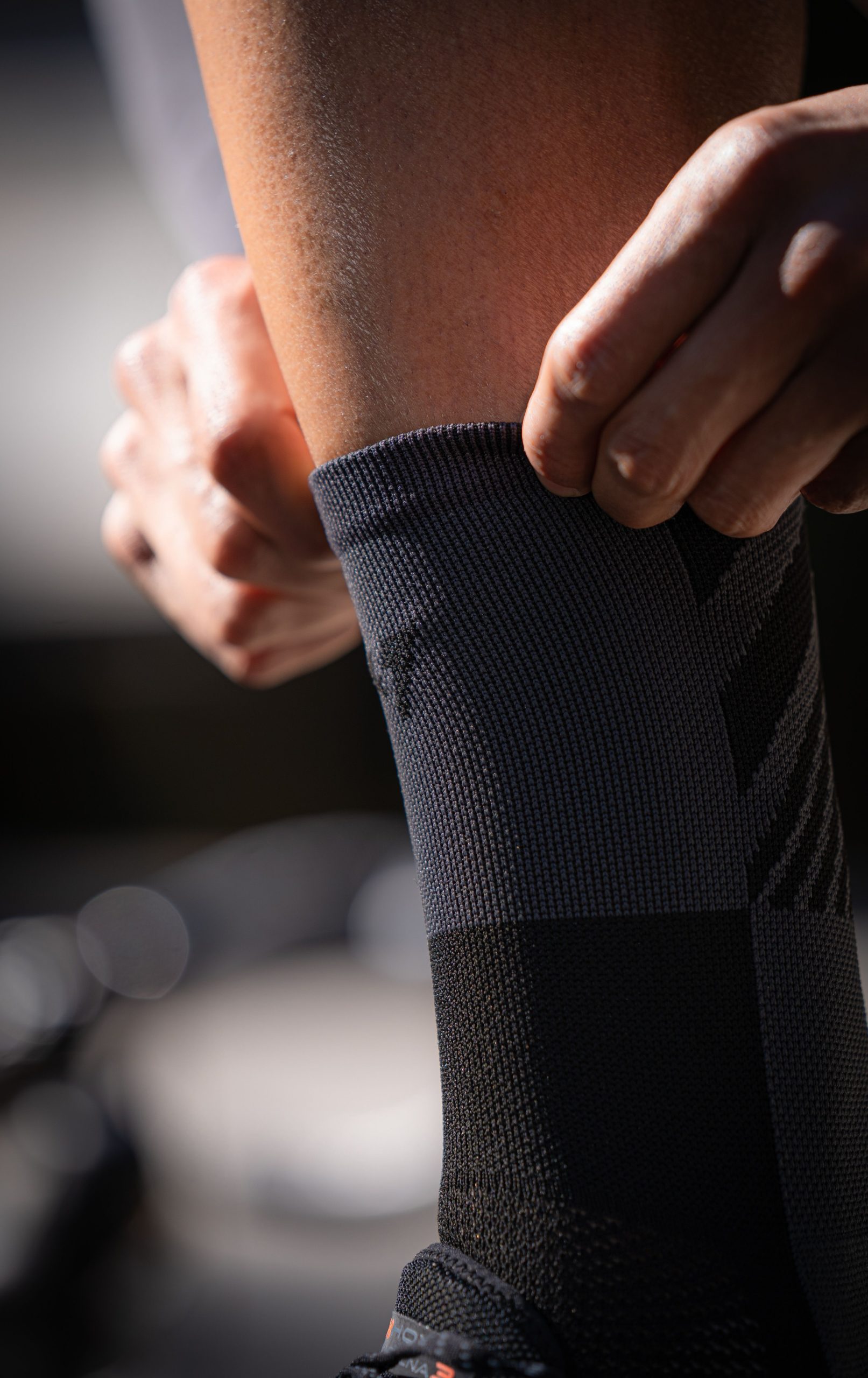 Close-up of someone adjusting a gray compression sock on their leg