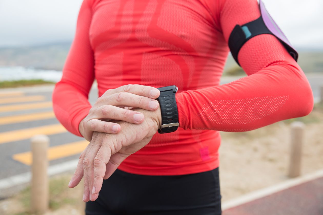 Runner checking their smartwatch mid-run outdoors