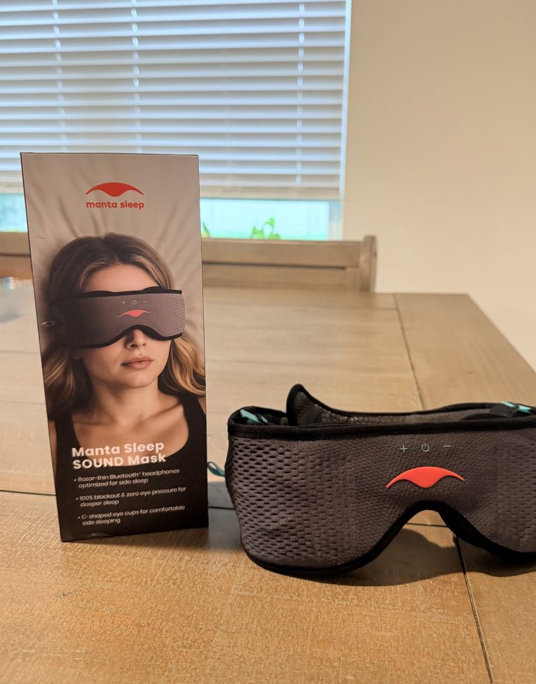 Gray Manta SOUND 2 sleep mask beside its Manta Sleep SOUND box on a wooden table.